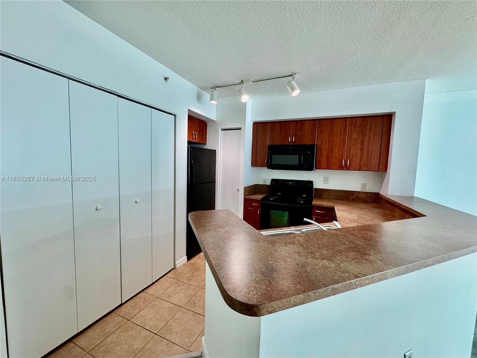 9201 Collins Avenue, Unit 323 Surfside, FL 33154 - Photo 35 of 46 a kitchen with stainless steel appliances granite countertop a refrigerator a sink a stove with wooden cabinets