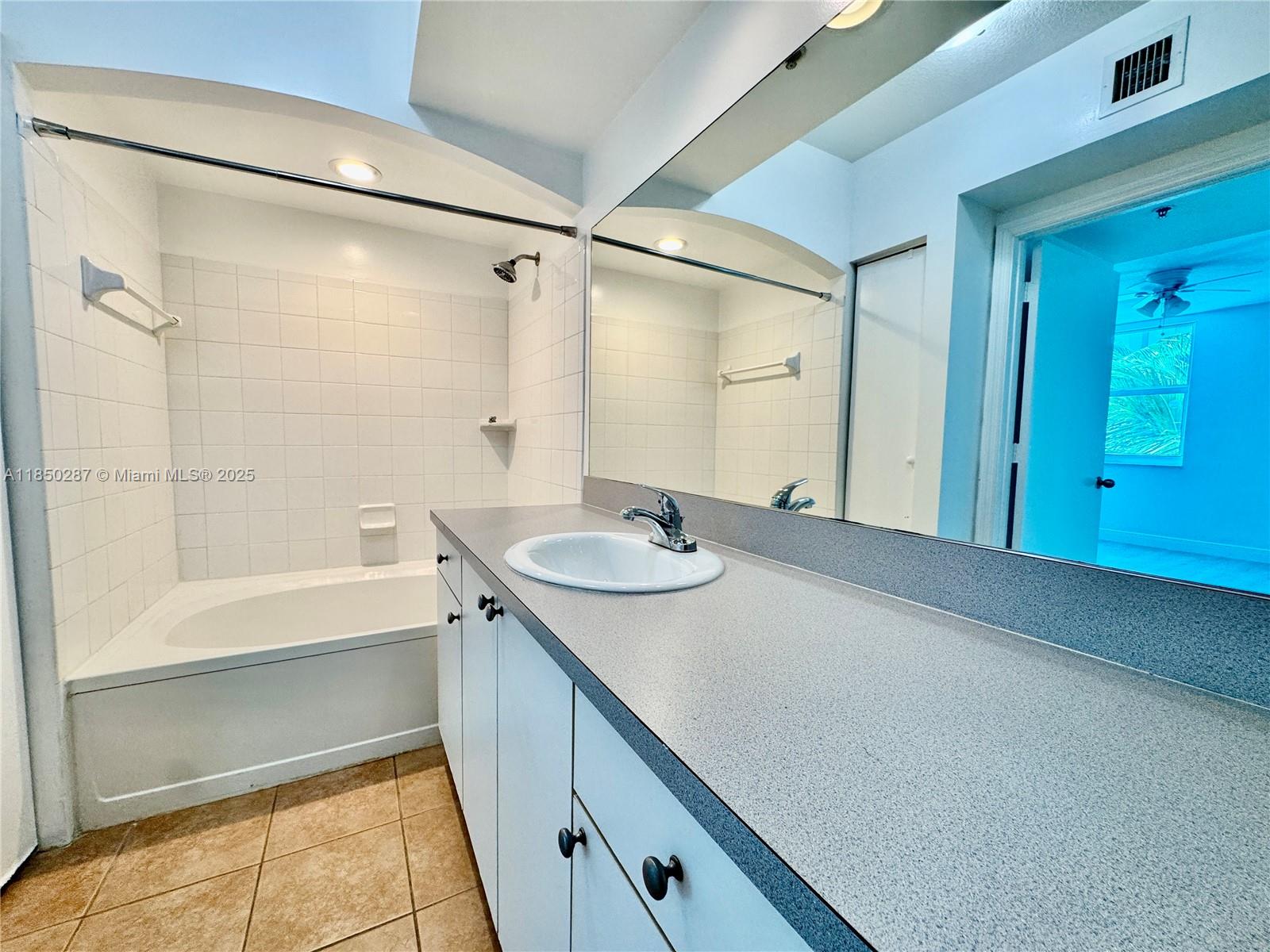 9201 Collins Avenue, Unit 323 Surfside, FL 33154 - Photo 39 of 46 a bathroom with a granite countertop sink a mirror and a bathtub