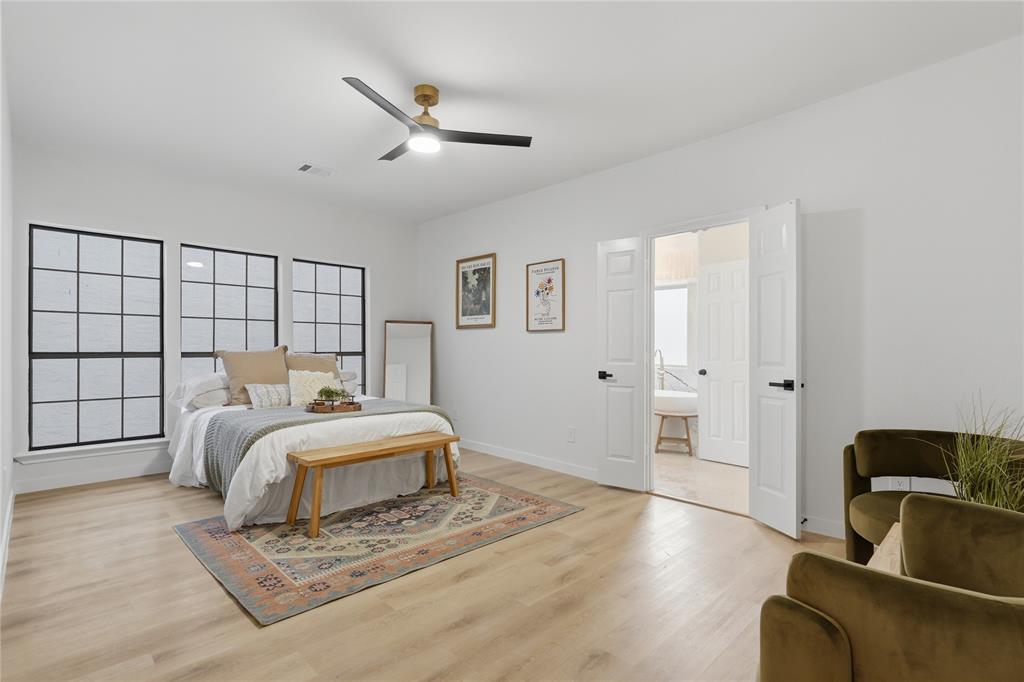 17118 Planters Row Addison, TX 75001 - Photo 15 of 18 Spacious room featuring light wood-finish flooring, three grid-patterned windows with black frames, and a contemporary ceiling fan with a gold and black finish