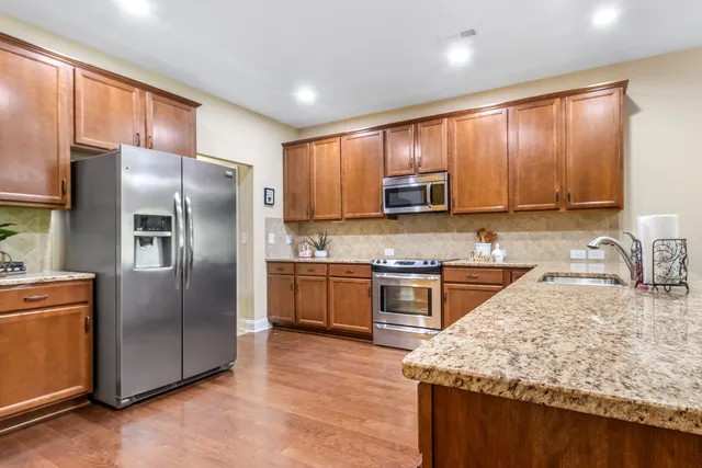a kitchen with kitchen island granite countertop wooden cabinets a refrigerator and a sink