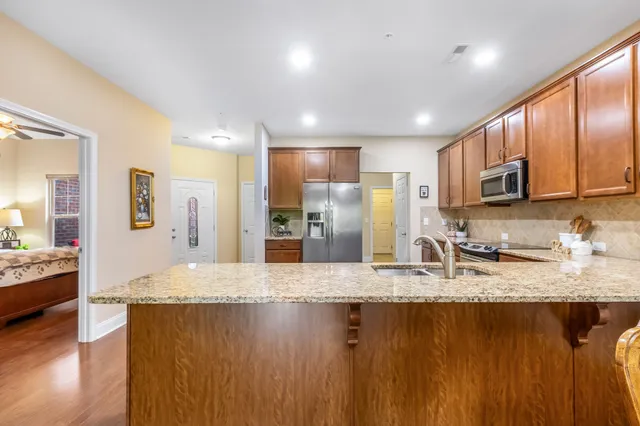 a view of a kitchen with kitchen island granite countertop a sink and refrigerator