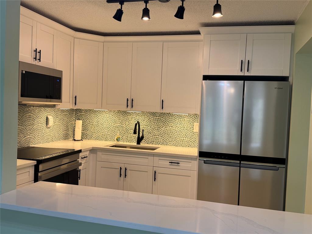 9300 Southwest 8th Street, Unit 215 Boca Raton, FL 33428 - Photo 18 of 43 a kitchen with stainless steel appliances a refrigerator sink and cabinets