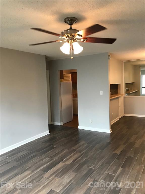 1604 Sharon Road West, Unit 22 Charlotte, NC 28210 - Photo 8 of 23 a view of an empty room with wooden floor and a kitchen