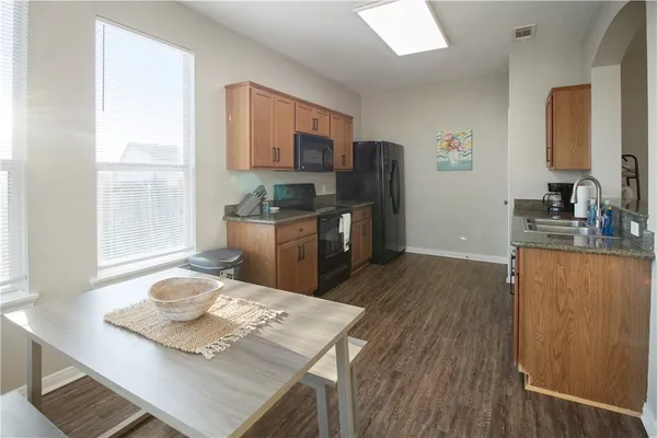 a kitchen with stainless steel appliances kitchen island granite countertop a sink dishwasher stove and refrigerator with wooden floor