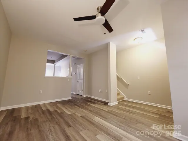 an empty room with wooden floor cabinet and windows