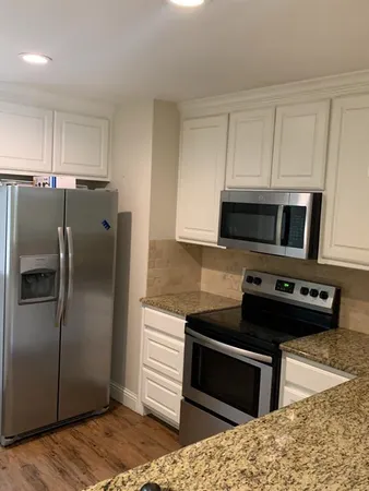 a kitchen with stainless steel appliances kitchen island granite countertop a refrigerator stove and microwave