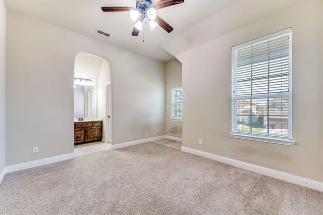 an empty room with windows and chandelier fan