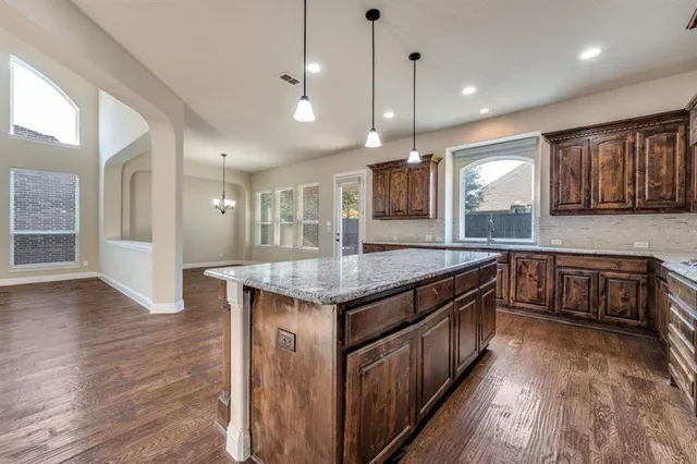 a kitchen with stainless steel appliances granite countertop wooden cabinets a stove a sink and a wooden floors