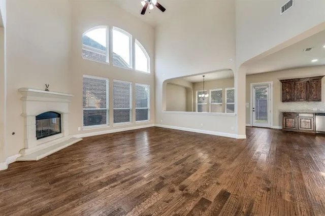 an empty room with wooden floor fireplace and windows