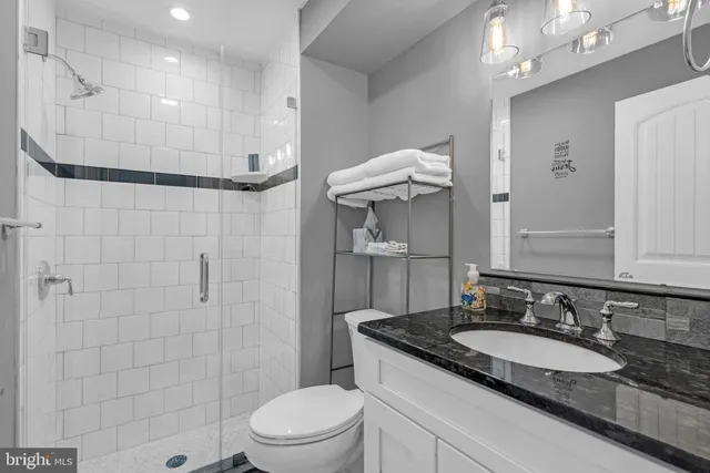 a bathroom with a granite countertop sink a toilet and shower