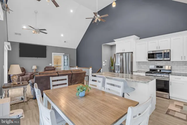 a kitchen with stainless steel appliances granite countertop a stove top oven a sink a dining table and chairs