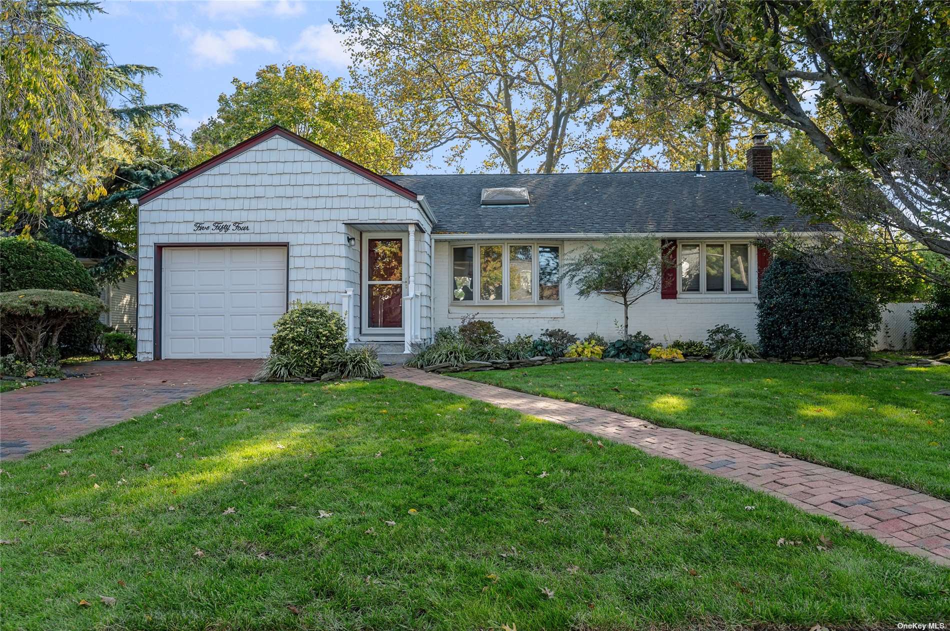 a view of a yard in front of a house with plants and large tree