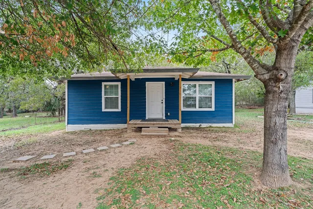 a view of a house with a yard and large tree