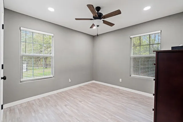 a view of an empty room with a window and wooden floor
