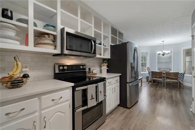 a kitchen with stainless steel appliances a stove a sink a refrigerator and chairs