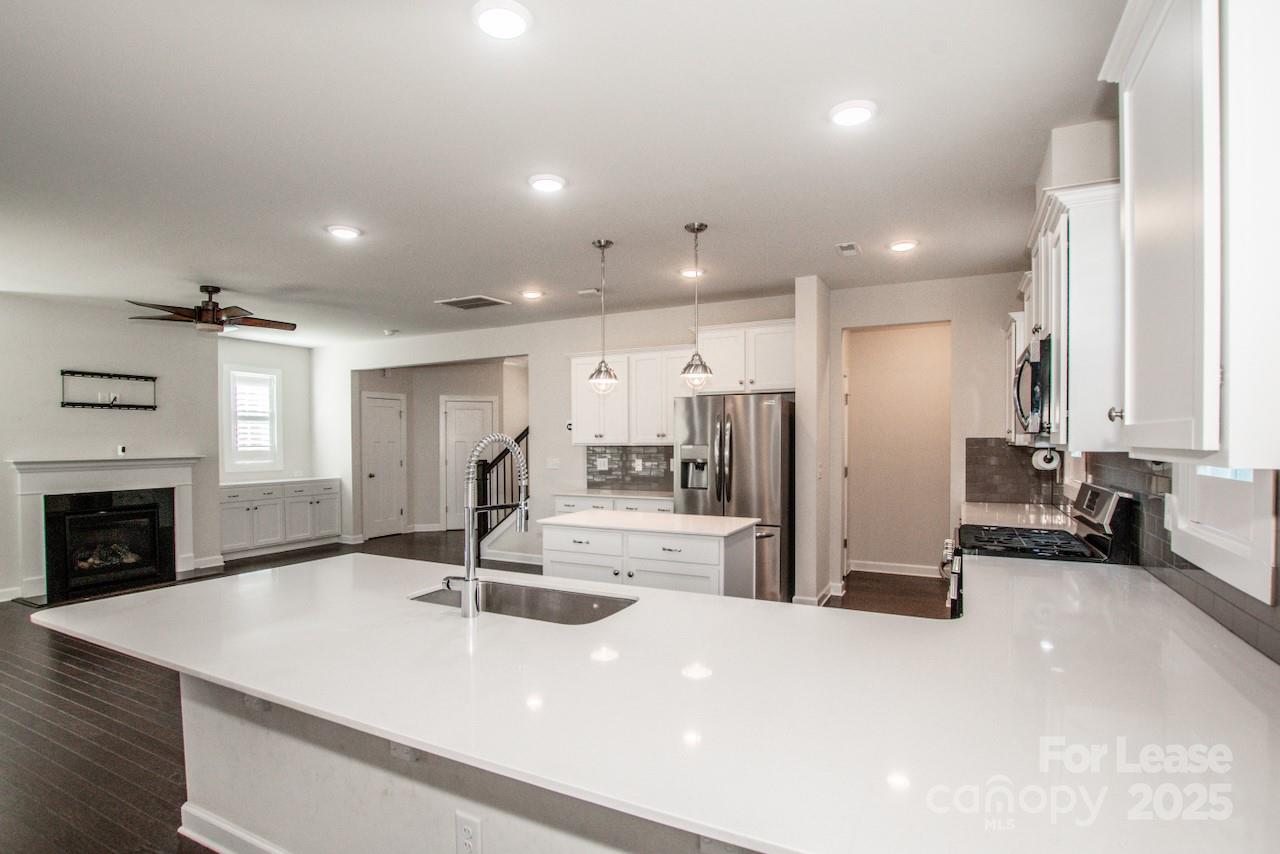 13218 Caite Ridge Road Davidson, NC 28036 - Photo 16 of 48 a view of a kitchen with kitchen island a sink stainless steel appliances and a fireplace