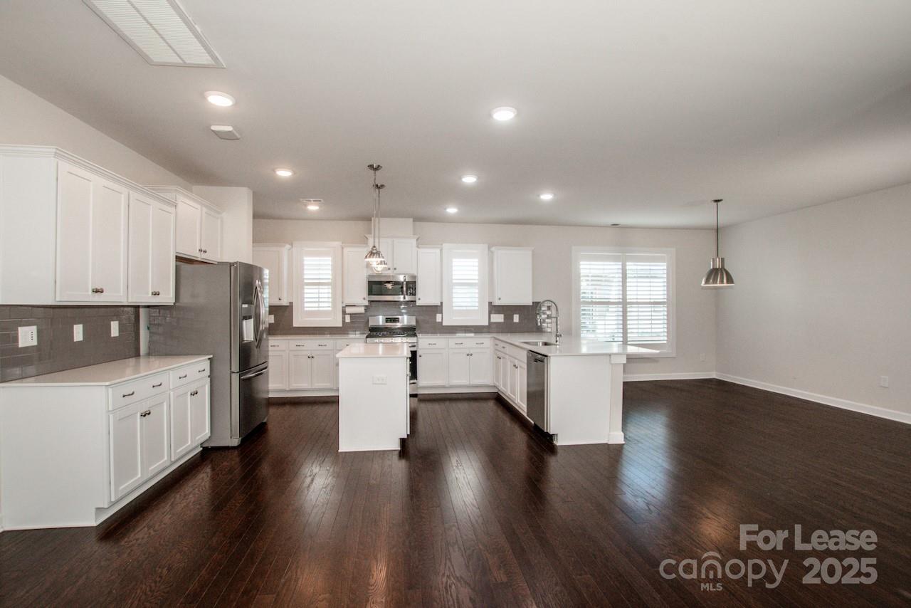 13218 Caite Ridge Road Davidson, NC 28036 - Photo 21 of 48 an open kitchen with white cabinets and wooden floor