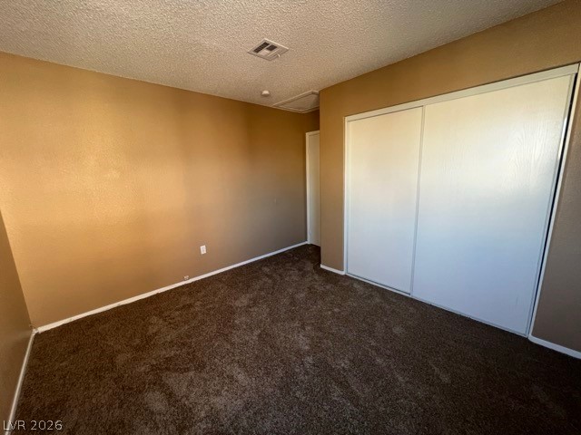 4140 North Compass Rose Way Las Vegas, NV 89108 - Photo 13 of 16 Unfurnished bedroom featuring dark colored carpet, a textured ceiling, and a closet