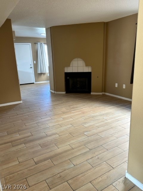 4140 North Compass Rose Way Las Vegas, NV 89108 - Photo 8 of 16 Unfurnished living room featuring light wood-style flooring, a fireplace, and a textured ceiling