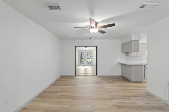 a view of an empty room with window and wooden floor