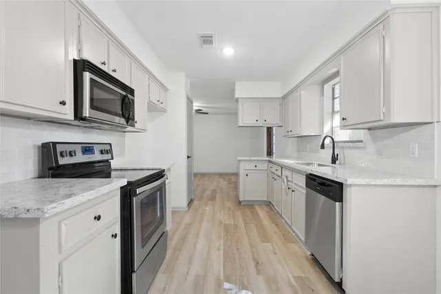 a kitchen with stainless steel appliances granite countertop a sink stove microwave and refrigerator