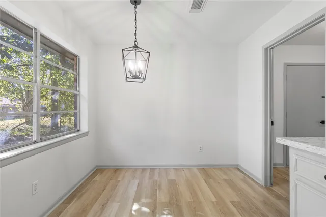 a view of empty room with wooden floor and window
