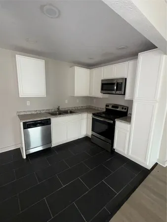 a kitchen with granite countertop a stove a microwave and a sink