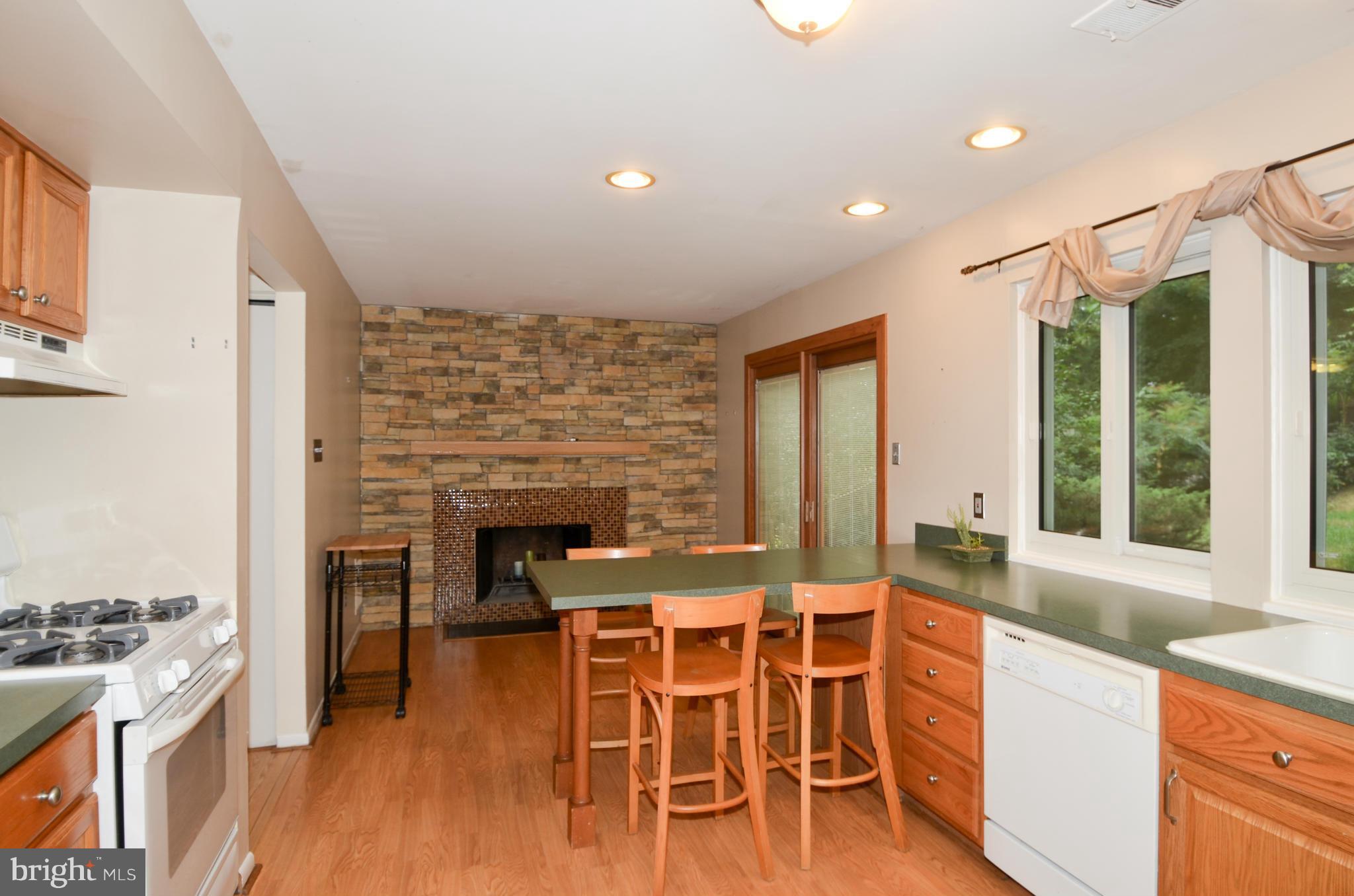 9608 Rocksparkle Row Columbia, MD 21045 - Photo 7 of 29 a open kitchen with granite countertop a stove dining table chairs and a fireplace