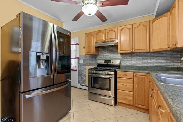 a kitchen with stainless steel appliances granite countertop a refrigerator a stove and a sink