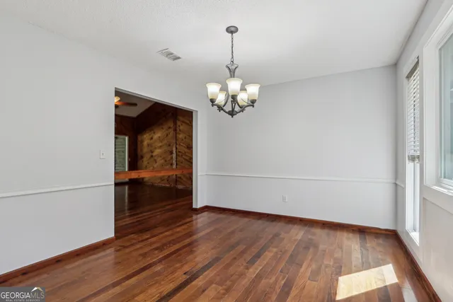 a view of a room with wooden floor and chandelier