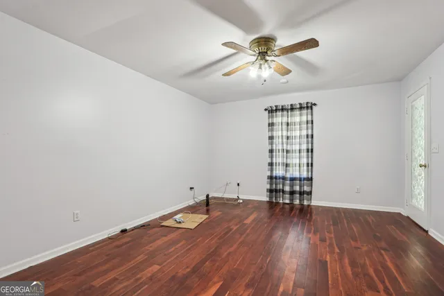 an empty room with wooden floor chandelier fan and windows