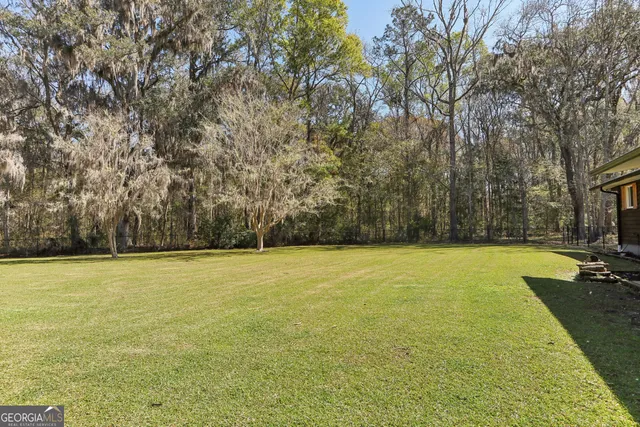 an aerial view of a house with swimming pool and trees all around
