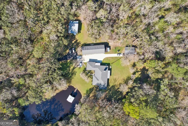 an aerial view of a house with swimming pool and trees