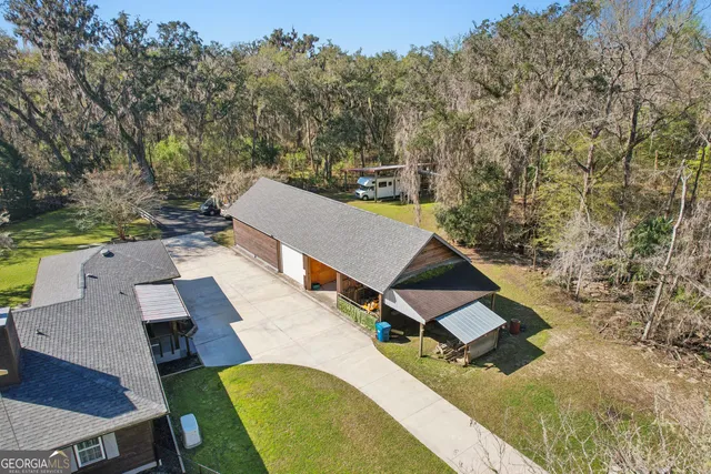 an aerial view of a house with swimming pool and large trees