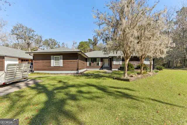 a view of a house with backyard and trees