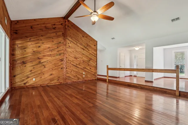 a view of an empty room with a window and wooden floor