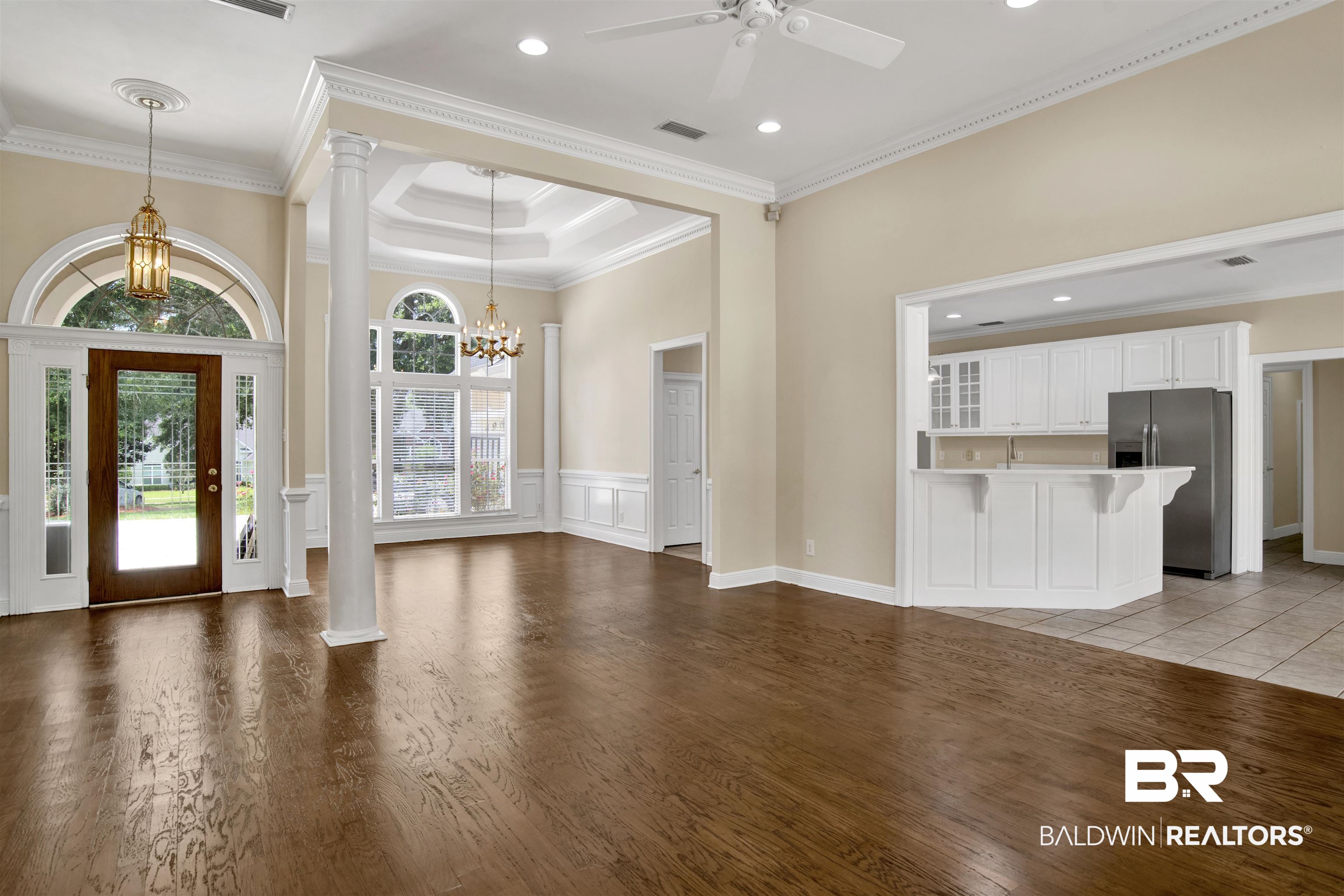 8847 Dawes Lake Road South Mobile, AL 36619 - Photo 3 of 47 Spacious living area featuring rich wood-finish flooring, a tray ceiling with a chandelier, and a prominent column