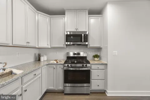 a kitchen with granite countertop white cabinets and stainless steel appliances