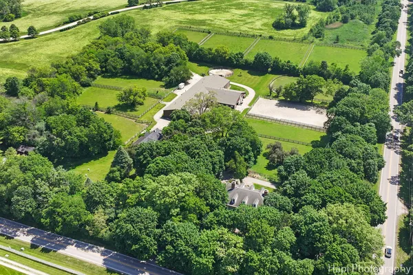 an aerial view of residential house with outdoor space and trees all around