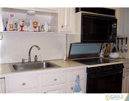 173 Midfield Road Colonia, NJ 07067 - Photo 8 of 25 a kitchen with white cabinets and black appliances