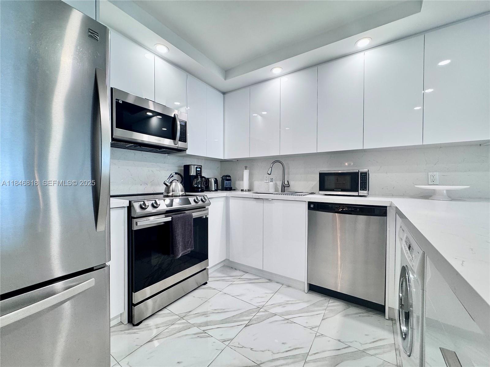 2851 Northeast 183rd Street, Unit 1508E Aventura, FL 33160 - Photo 3 of 27 a kitchen with stainless steel appliances granite countertop a stove a microwave and a refrigerator