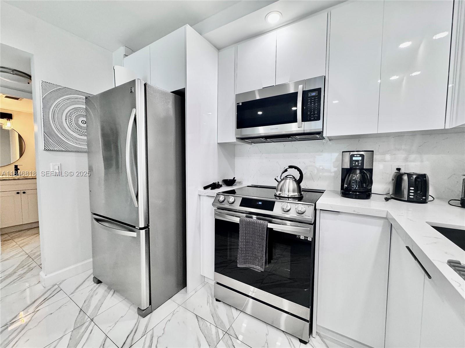2851 Northeast 183rd Street, Unit 1508E Aventura, FL 33160 - Photo 9 of 27 a kitchen with stainless steel appliances a refrigerator stove and microwave