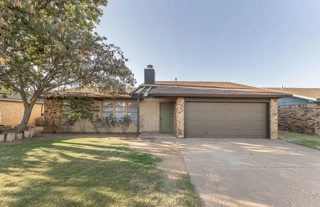 a view of a house with a small yard and a large tree