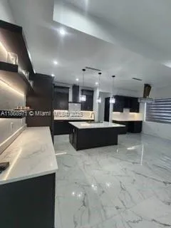 a large white kitchen with a large counter top appliances and cabinets