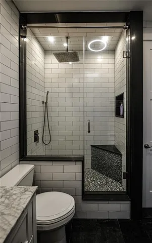 a bathroom with a granite countertop sink a toilet and shower