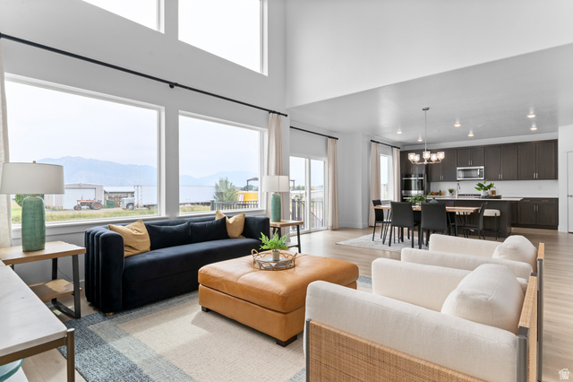 1418 West 2350th South, Unit 15 Perry, UT 84302 - Photo 4 of 22 Spacious open-concept living area featuring high ceilings, expansive windows with mountain scenery, and light wood-finish flooring