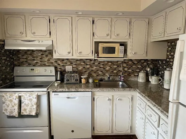 a kitchen with granite countertop a sink stove and cabinets