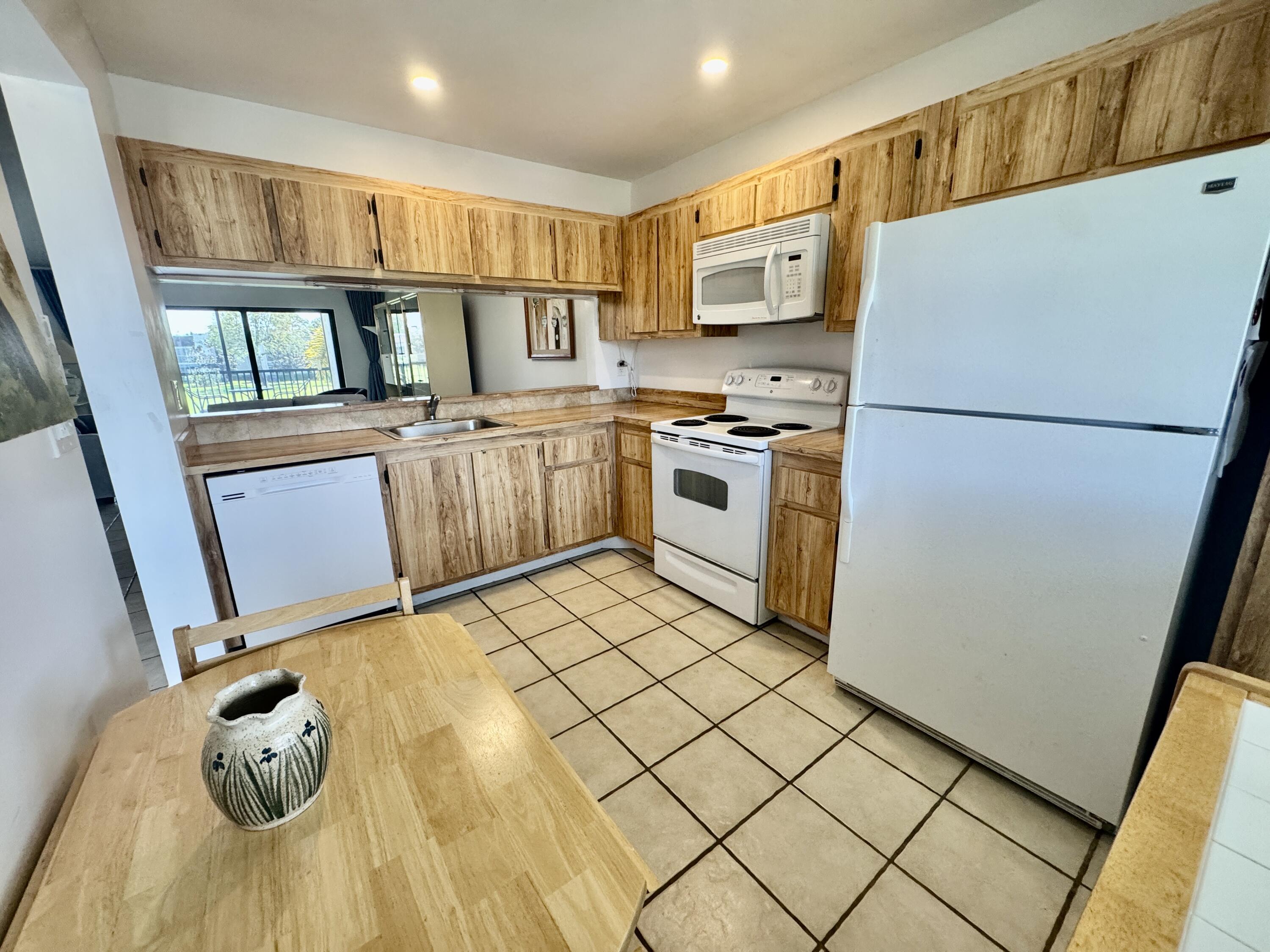 2840 Casa Way, Unit 201 Delray Beach, FL 33445 - Photo 9 of 26 a kitchen with a refrigerator a stove top oven and a sink