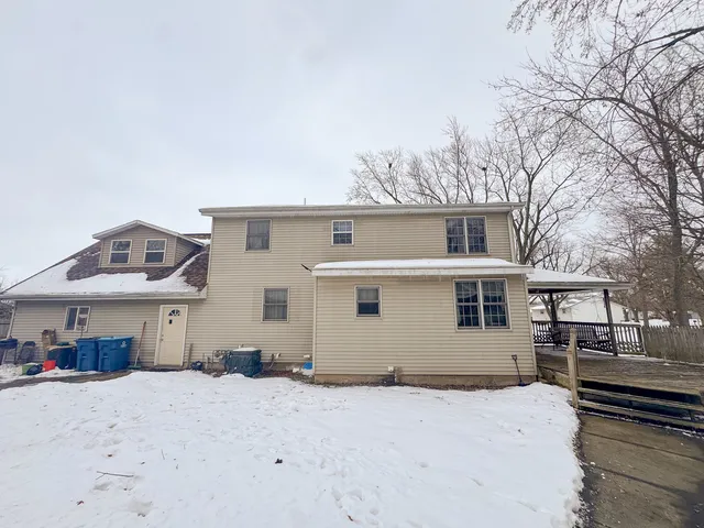 a front view of a house with yard and trees in the background