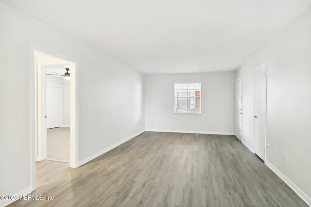 an empty room with wooden floor and windows